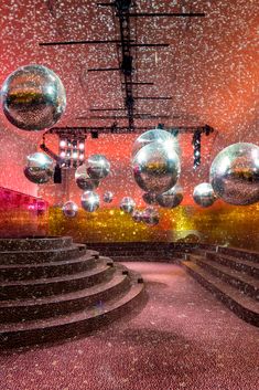 an empty stage with shiny balls hanging from the ceiling and steps leading up to it