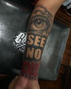 a person with a tattoo on their arm that says see no evil and an eye