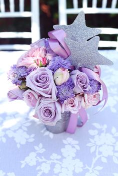 a bouquet of purple roses and lavender carnations with a star decoration on top