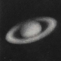 a black and white image of a ringed object in the dark night sky with only one light visible