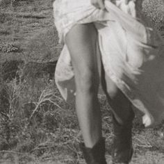 black and white photograph of a woman walking in the grass