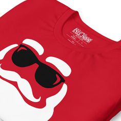 Get into the holiday spirit with our "Chill Santa with Sunglasses" graphic tee! This hilarious Christmas t-shirt features Santa himself sporting a stylish pair of black shades and a classic white beard. Because even Santa needs to chill in the North Pole! Show off your love for Santa Claus and Christmas with this tee that combines holiday cheer with a touch of cool. Perfect for those who think Christmas should be as fun as it is festive! Who knew Santa could look so good in aviators?• 100% combe Casual Christmas Fan Merchandise Tops, Sunglasses Graphic, Black Shades, White Beard, The North Pole, Santa Face, Christmas T Shirt, North Pole, Shades Of Black