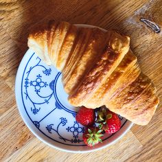 croissants and strawberries sit on a plate