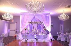 a banquet hall with chandeliers and white drapes