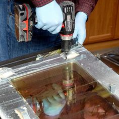 a man in blue gloves is using a drill to cut through the metal frame with a machine