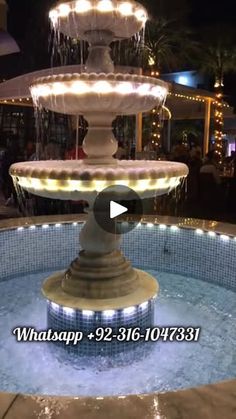 the fountain is lit up with lights and water