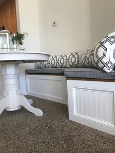 a white table and bench with pillows on it