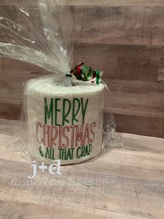 a white christmas cake wrapped in plastic on top of a wooden table with the words merry christmas and all that crap