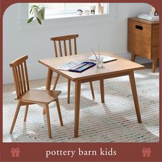 a wooden table with two chairs and a book on it in front of a window