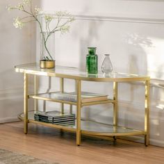 a glass table with books and vases on it in front of a white wall