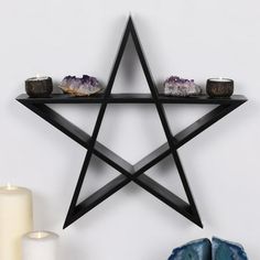 a shelf with candles, rocks and a star shaped object hanging on it's wall