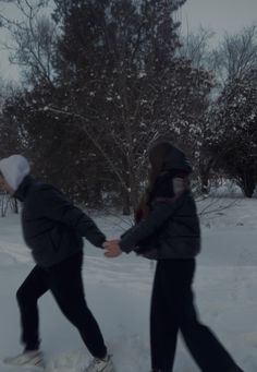 two people walking in the snow holding hands