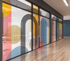 an empty room with colorful glass walls and wood flooring that is painted multicolored