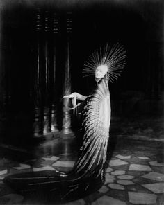 an old photo of a woman dressed in black and white with feathers on her head