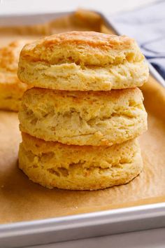 three biscuits stacked on top of each other in front of a baking pan with one biscuit