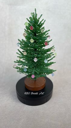 a small green christmas tree sitting on top of a wooden stand