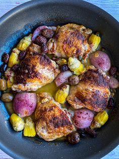 a pan filled with chicken, potatoes and olives