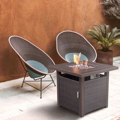 two wicker chairs sit next to an outdoor fire pit