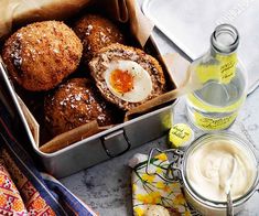 an open tin box filled with baked goods next to a bottle of yogurt