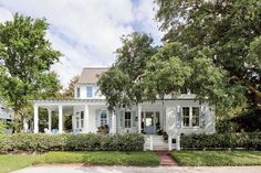 a white house with trees and bushes around it