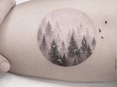 a woman's thigh with trees and birds in the sky on her right side