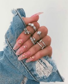 a woman's hand with five different rings on her fingers and one is wearing a denim jacket