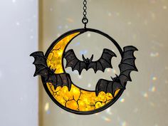 a yellow and black moon with bats hanging from it's side in front of a white wall