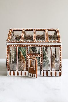 a gingerbread house shaped cookie box with christmas decorations on the front and sides, sitting on a white surface