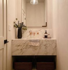 a bathroom with a marble counter top and sink under a hanging light above it is decorated with flowers