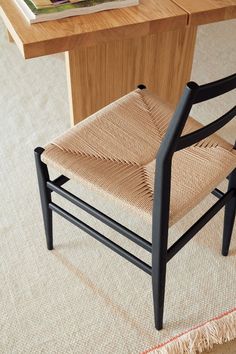 a chair sitting on top of a rug next to a wooden table with a book