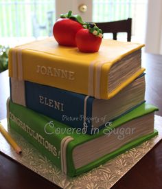 a stack of books sitting on top of a wooden table next to a red apple