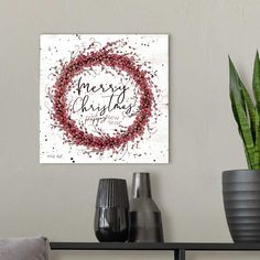 a christmas wreath with the words merry and happy on it is displayed in front of a white wall