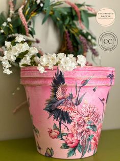 a pink flower pot sitting on top of a table next to a green planter