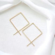 Catch everyone's eye with these chic, minimalist square-wire hoop earrings made of glinting gold. Classy and modern, these statement earrings are sure to turn heads! .925 Sterling Silver Wire Earrings measure 2.5" long Polished to a High Shine Sent in a Ribboned Gift Box with Polishing Cloth Handmade in Montana Modern Gold-plated Linear Earrings With Ear Wire, Modern Gold Square Earrings, Handmade Square Minimalist Earrings, Modern 14k Gold-filled Linear Earrings, Modern Square Tarnish-resistant Hoop Earrings, Silver Wire Earrings, Wire Hoop Earrings, Open Hoop Earrings, Earring Cards