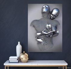 two metal figures are hugging each other in front of a painting on the wall above a table