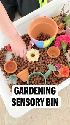 a child's hands reaching into a container filled with fake flowers and gardening items