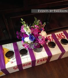 purple and white flowers are in a vase on a box