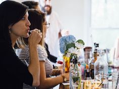 a group of people sitting around a table with drinks and flowers in vases on it