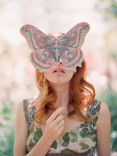 a woman holding a butterfly on top of her head