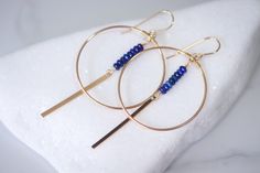 Introducing the stunning gleaming 14k Gold Filled Handcrafted Hoops, a true masterpiece created by hand with the finest materials and attention to detail. These exquisite hoops are adorned with a row of mesmerizing, bright blue Lapis Lazuli gemstones that add a touch of color and vibrancy to the piece. The 14k gold filled dangling bar beautifully complements the Lapis Lazuli stones and adds a touch of sophistication and elegance to the overall design. The earrings are designed with great movemen Fine Jewelry 14k Gold Linear Earrings, Elegant 14k Gold Gemstone Hoop Earrings, 14k Gold Round Linear Earrings Fine Jewelry, Round 14k Gold Linear Earrings - Fine Jewelry, Elegant Blue 14k Gold Hoop Earrings, 14k Gold Round Linear Earrings, 14k Gold Gemstone Hoop Jewelry, Modern 14k Gold Dangle Hoop Earrings, Fine Jewelry 14k Gold Filled Round Earrings