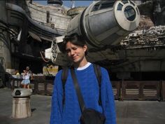 a young man standing in front of a star wars ship