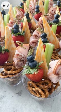 several small trays filled with pretzels, strawberries and other food items