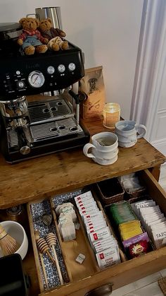 an espresso machine sitting on top of a wooden table filled with coffee cups