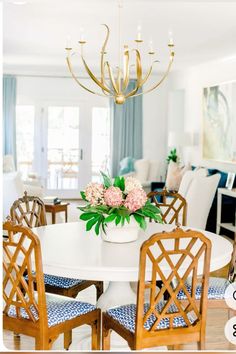 a dining room table with chairs and a chandelier hanging from the ceiling above it