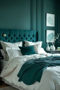 a bedroom with green walls and white linens on the bed, along with two vases filled with flowers