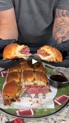 a man holding two large sandwiches on top of a plate