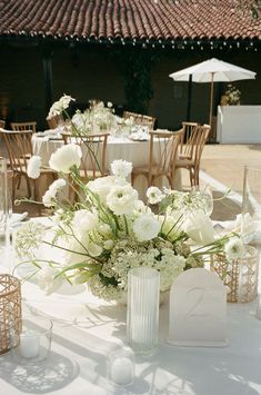 the table is set with white flowers and candles for an elegant wedding reception in italy