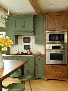 a kitchen with green cabinets and an oven in the center, surrounded by stools