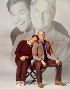 two men sitting on a chair in front of a photo