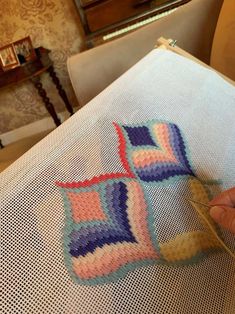 someone is working on a crochet project in their living room with the help of a pair of scissors